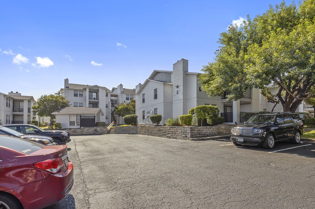 a parking lot in front of an apartment building with cars parked