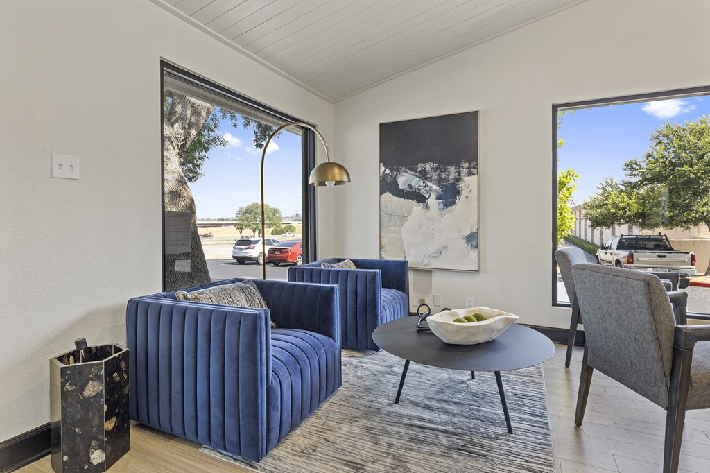 a living room with blue chairs and a table with a bowl of food on it