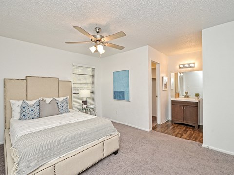 A bedroom with a large bed and a ceiling fan.