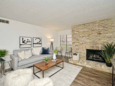 A living room with a grey couch, a wooden coffee table, a fireplace, and a rug.