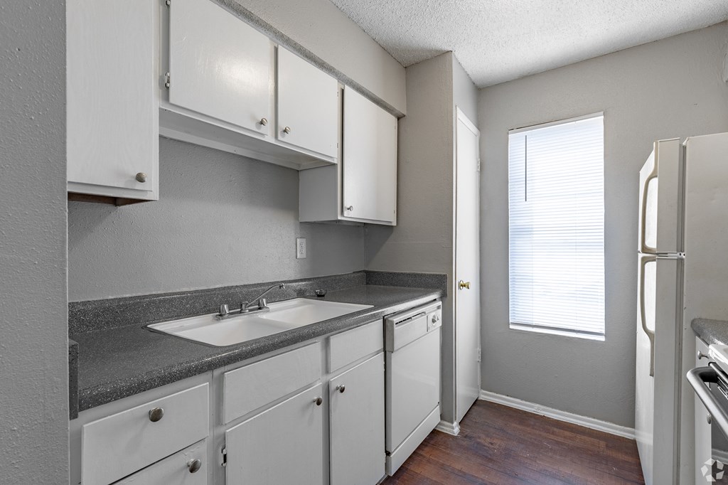 a kitchen with white cabinets and gray countertops at The Frederick, San Antonio