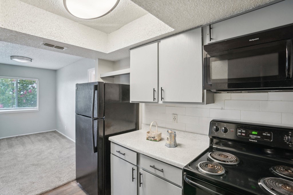 a kitchen with light colored cabinets and black appliances
