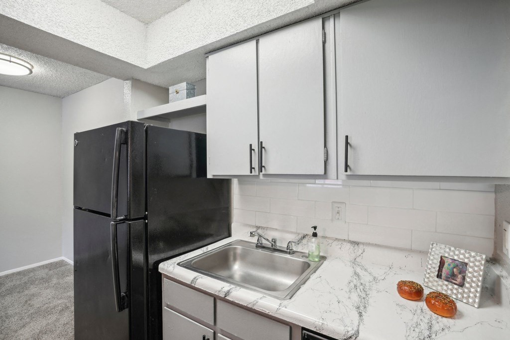 a kitchen with light color cabinets and a sink and a refrigerator