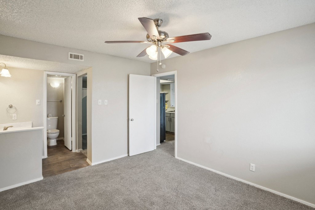 a bedroom with a ceiling fan and a bathroom