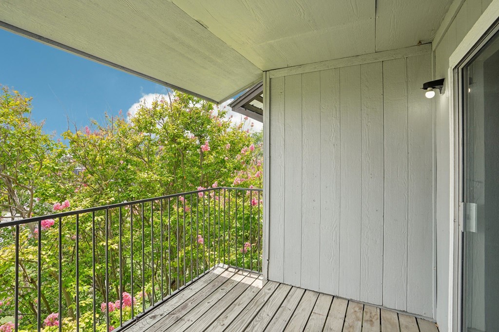 the balcony has a view of the garden and the trees