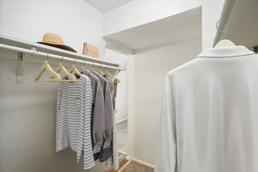 a closet with a white shirt and a hat hanging on a rack