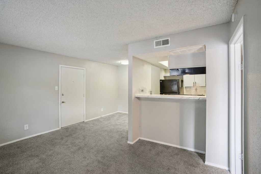 the living room and kitchen of an apartment with a carpeted floor