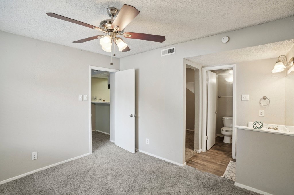 a bedroom with a ceiling fan and a bathroom
