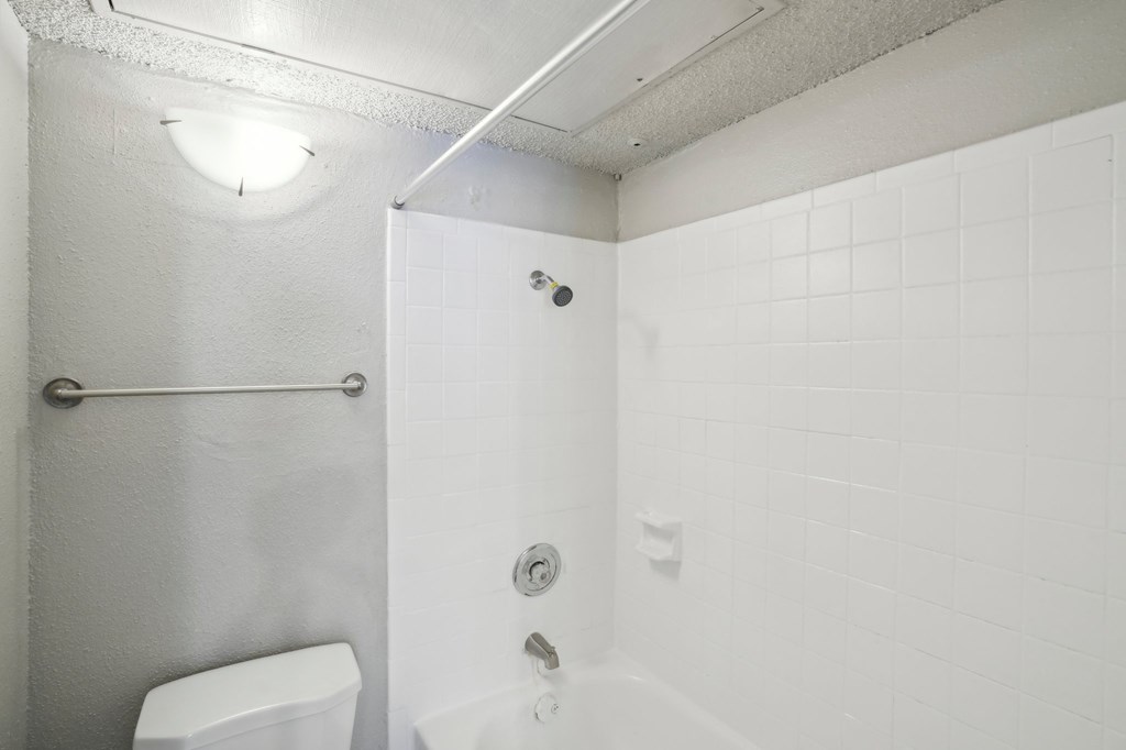 a white bathroom with a toilet and a shower