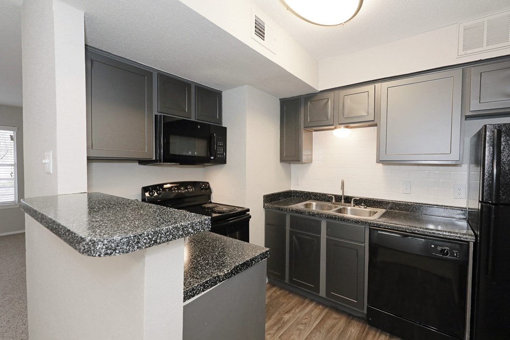 a kitchen with granite countertops and black appliances