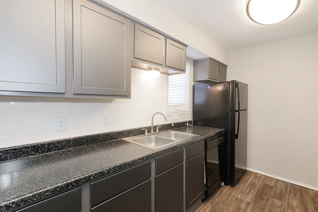 a kitchen with dark cabinets and a black refrigerator