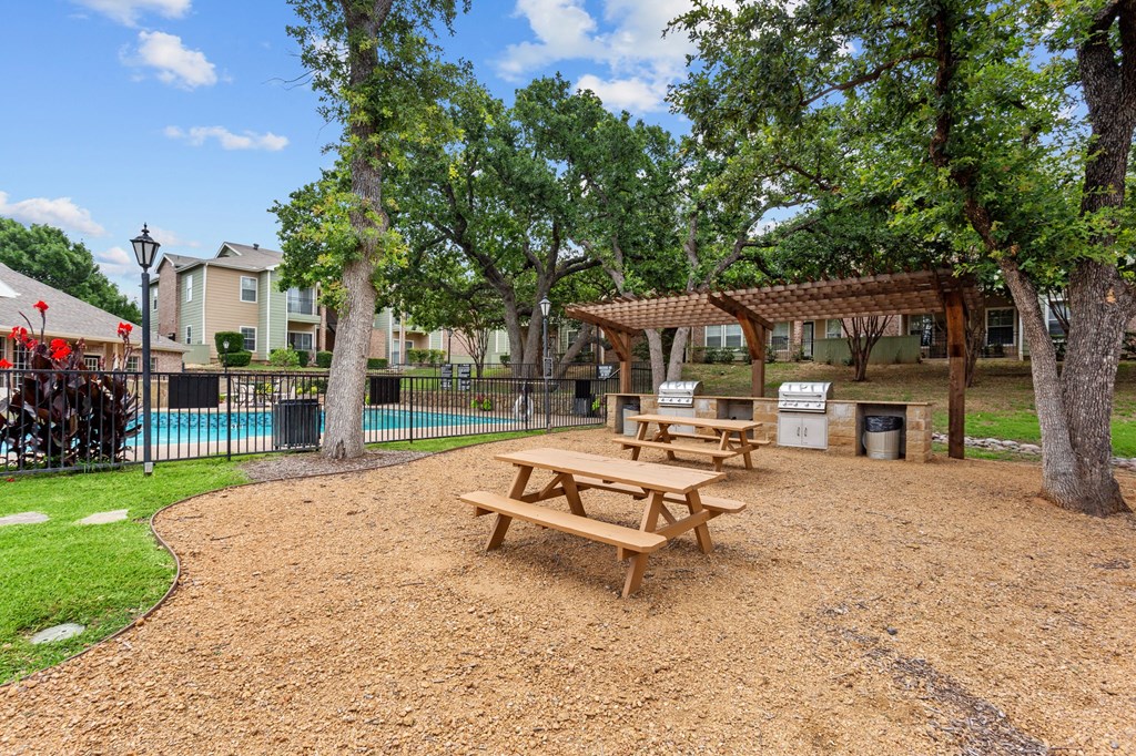 a picnic area with benches next to a swimming pool at Southgate Glen, Weatherford, TX