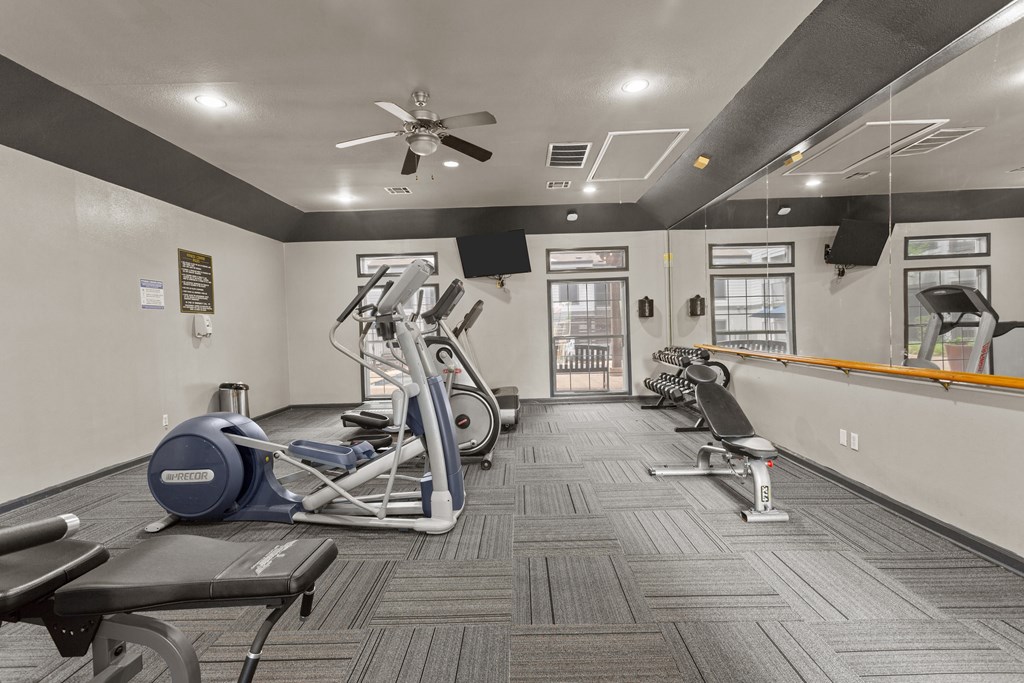 A gym with a variety of equipment including treadmills, elliptical machines, and weight machines.