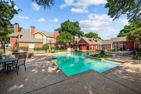 A pool surrounded by a patio and trees.
