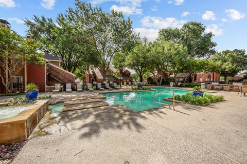 A pool surrounded by trees and a building in the background.