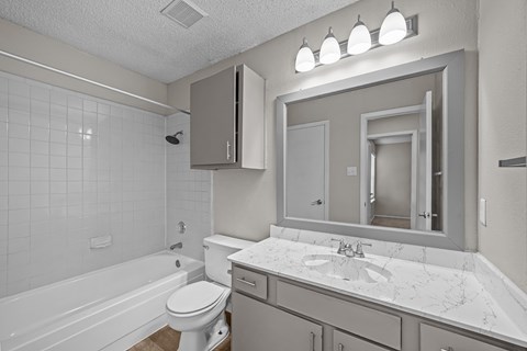 A white bathroom with a tub, toilet, and sink.