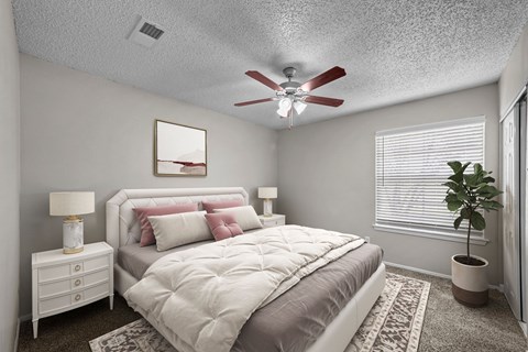 A bedroom with a bed, nightstand, and a ceiling fan.