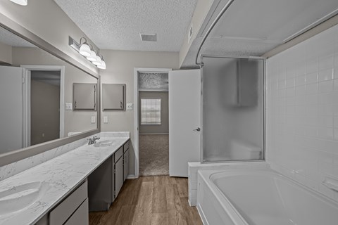 A white bathroom with a tub, sink, and mirror.
