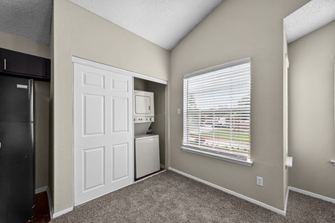 A room with a white door, a window with blinds, and a black refrigerator.