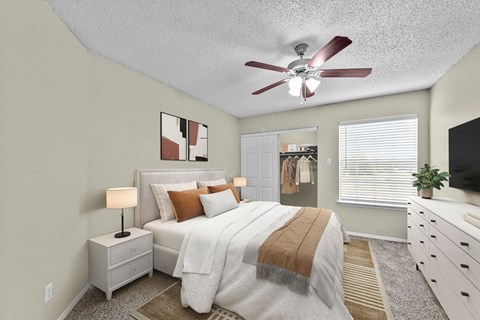 A bedroom with a bed, nightstand, and a ceiling fan.