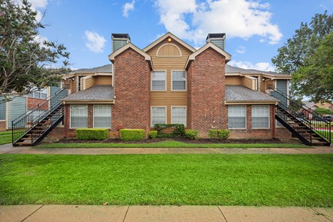 A brick house with a green lawn in front.