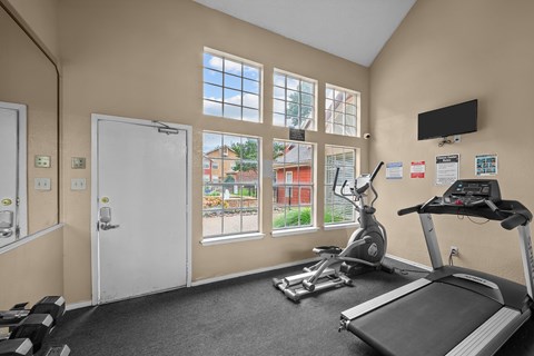A gym room with a treadmill, exercise bike, and other equipment.