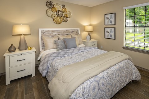A bedroom with a large bed and a white nightstand with two lamps.
