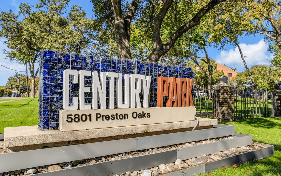 A sign for Century Park stands in front of a tree.