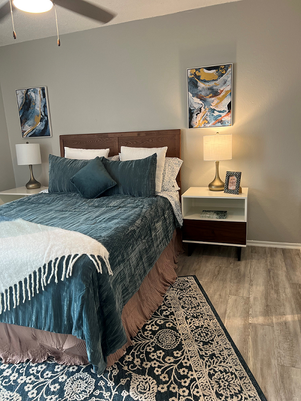 a bedroom with a bed and a nightstand with a lamp