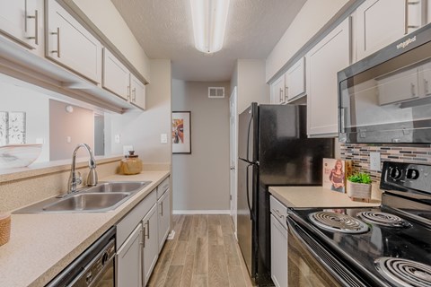 A kitchen with a black fridge and stove top oven.