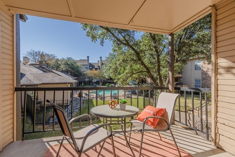 Covered balcony with pool view and seating at Pinehurst Place Apartments, Mesquite, TX 75150