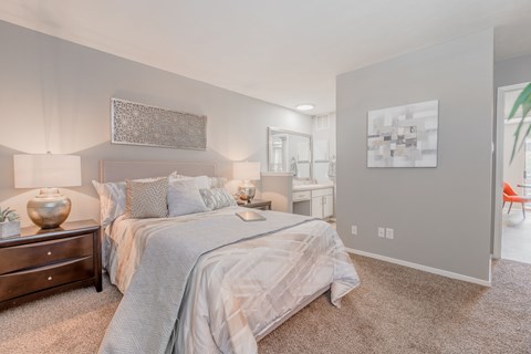 A bedroom with a large bed and a dresser with a vase on top.