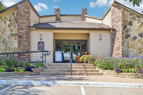 A house with a stone wall and a black sign that reads "211" is shown.