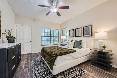 A bedroom with a bed, dresser, and a ceiling fan.