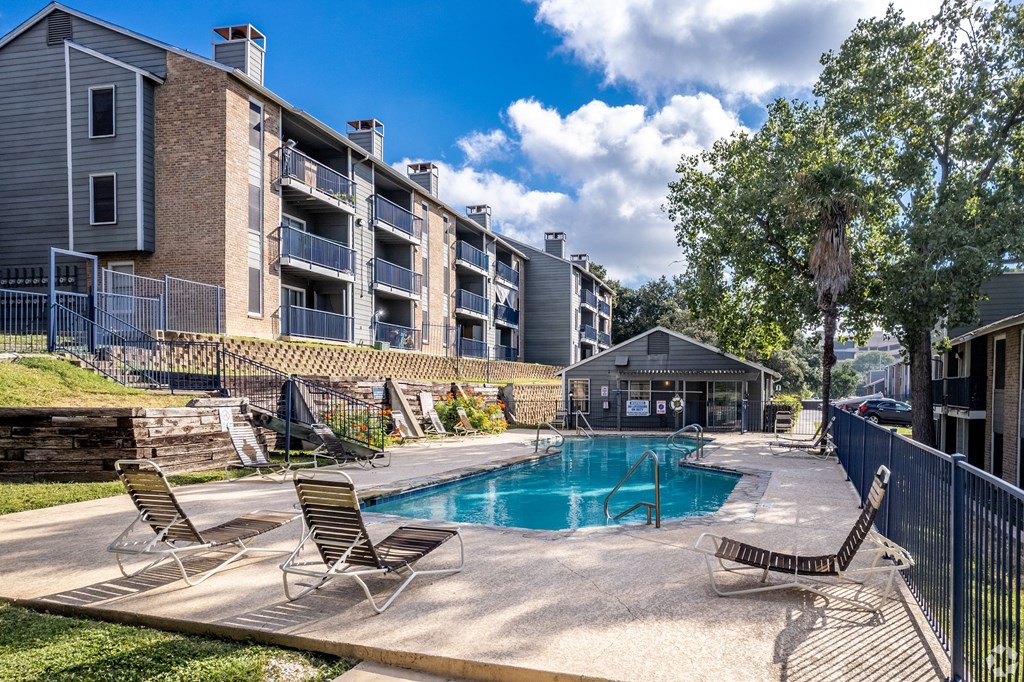 a swimming pool with chaise lounge chairs and a building in the background at The Frederick, San Antonio Texas