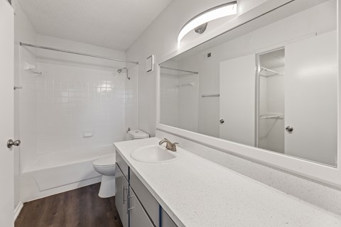 A white bathroom with a toilet, sink, and mirror.