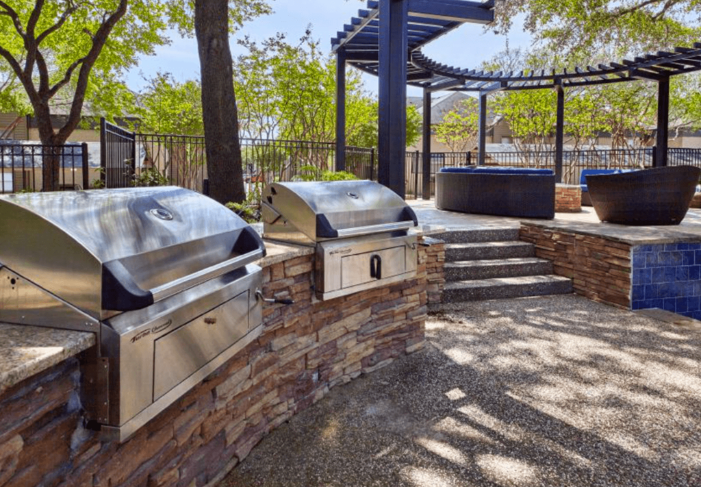 a patio with two bbq grills and a pergola