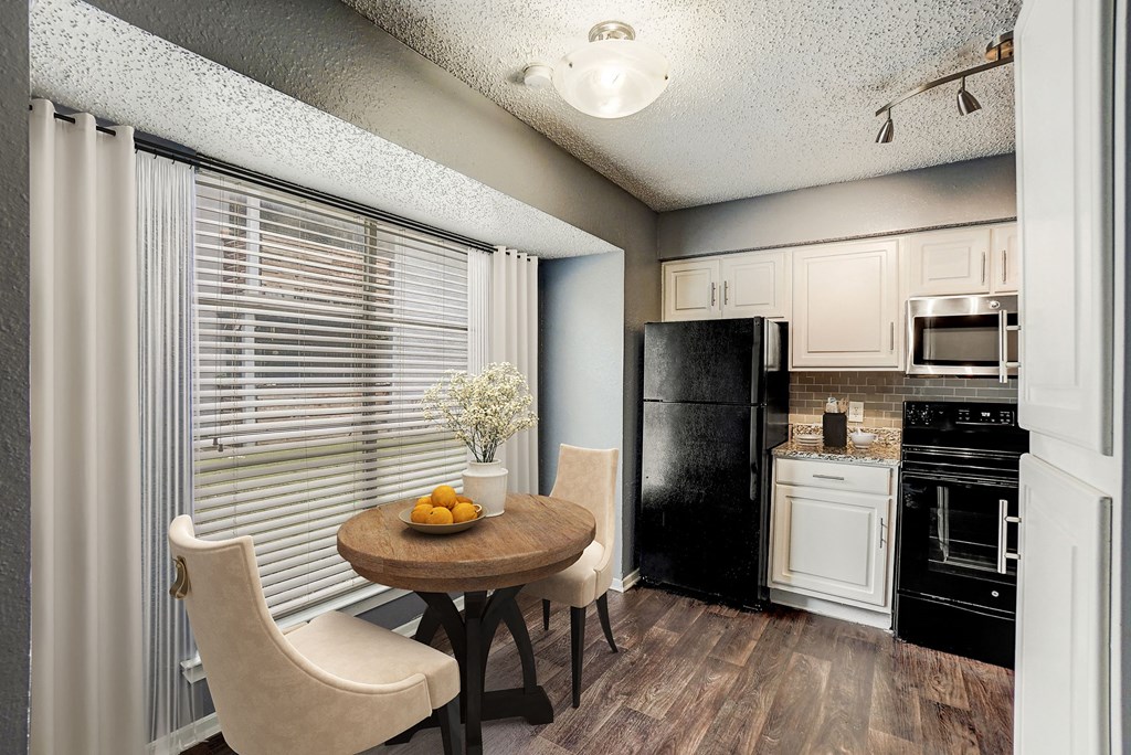 a kitchen with a table and chairs and a black refrigerator