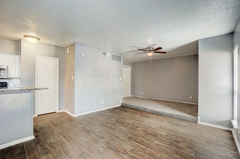 an empty living room and kitchen with a ceiling fan