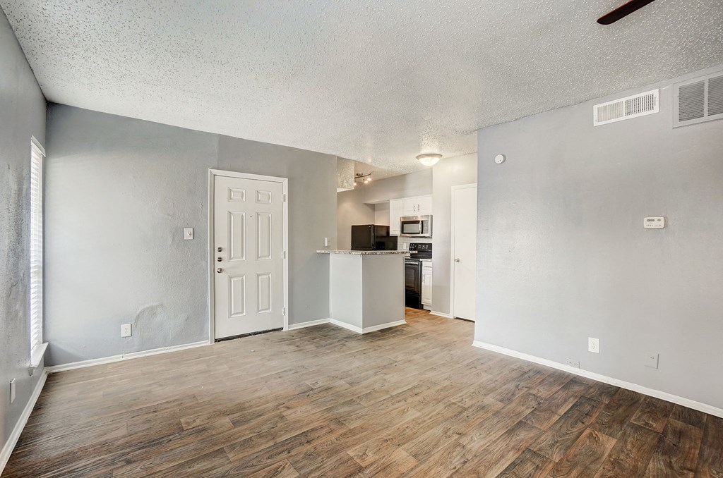 the living room and kitchen of an apartment with a hard wood floor