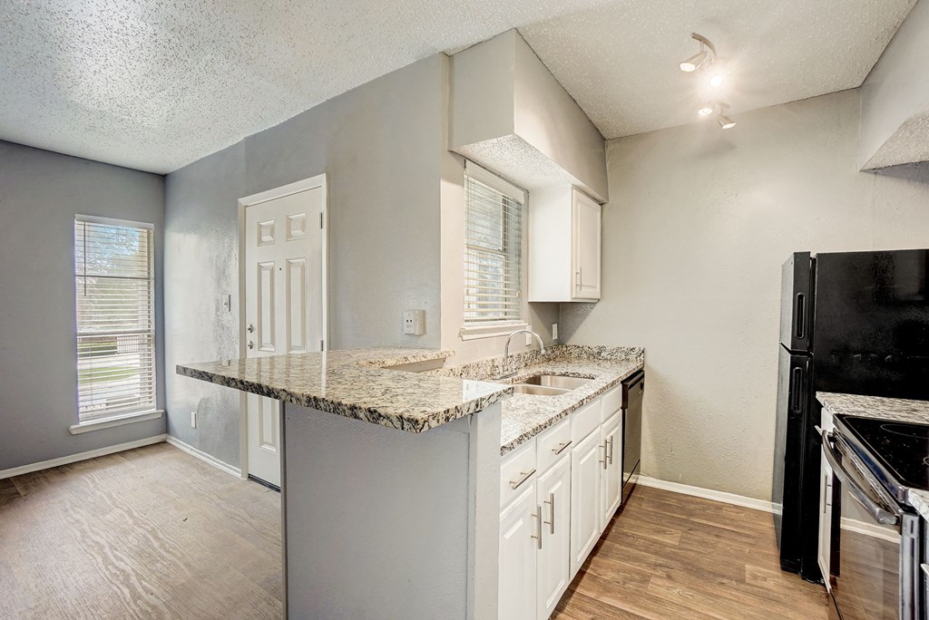 an empty kitchen with a granite counter top and white cabinets