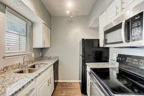 a kitchen with granite counter tops and black appliances