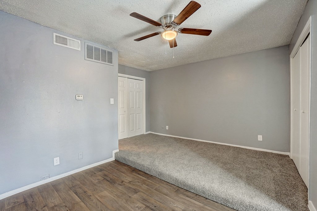 the spacious living room has a ceiling fan and a carpet