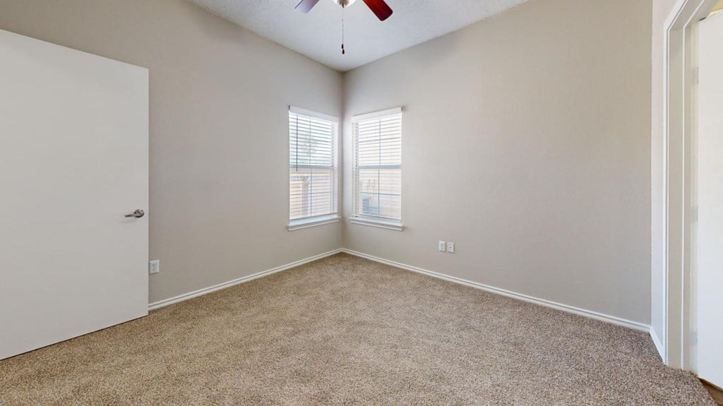 an empty bedroom with two windows and a ceiling fan at Southgate Glen, Texas