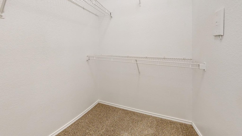 a walk in closet with a shelf on the wall and a carpeted floor at Southgate Glen, Weatherford, 76086