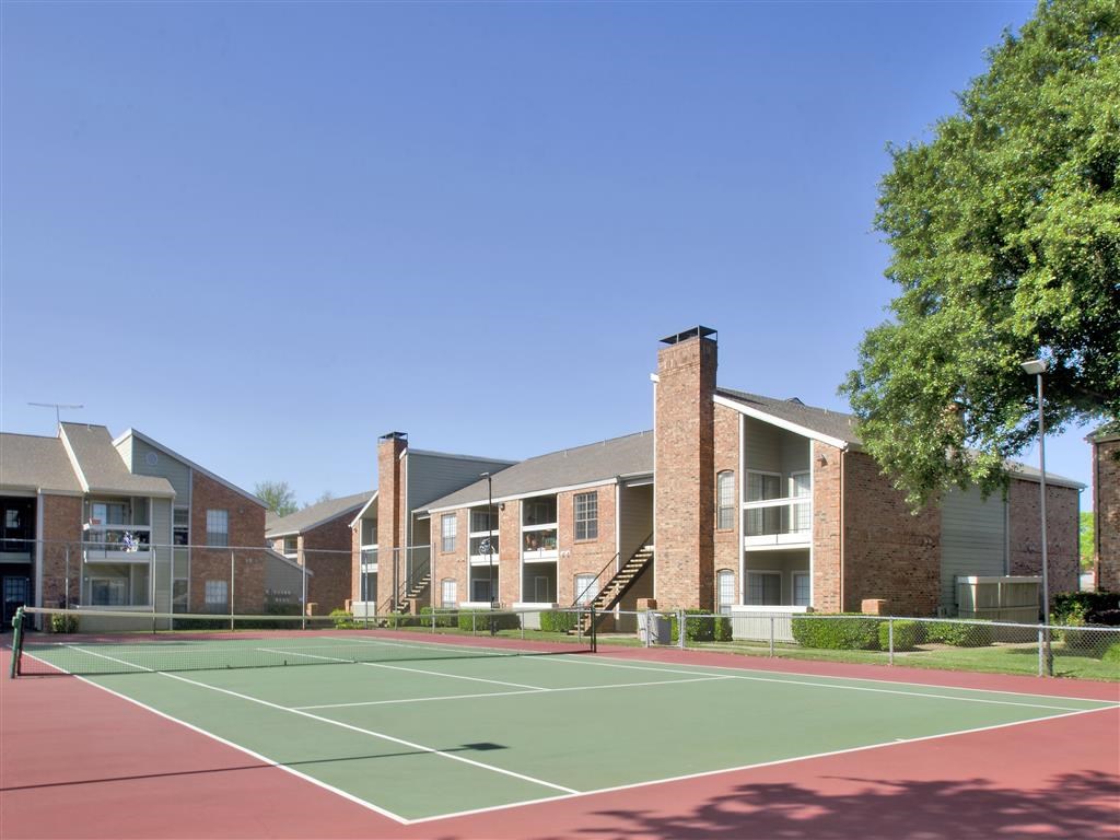a tennis court with apartments in the background