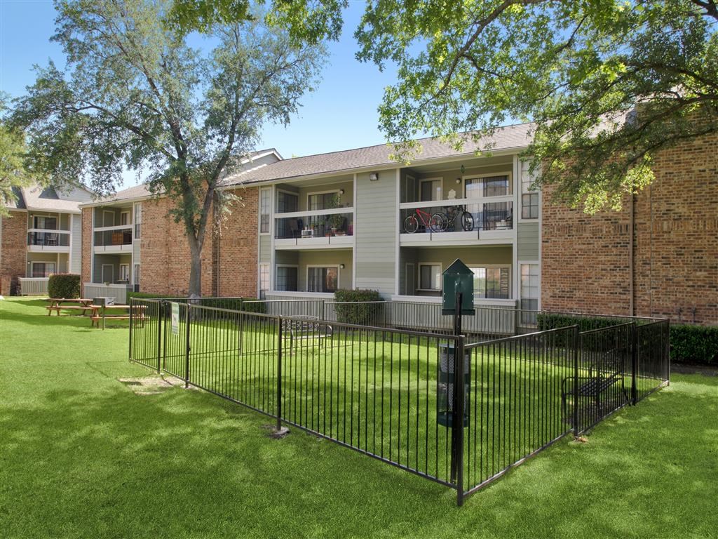 an apartment building with a wrought iron fence and grass
