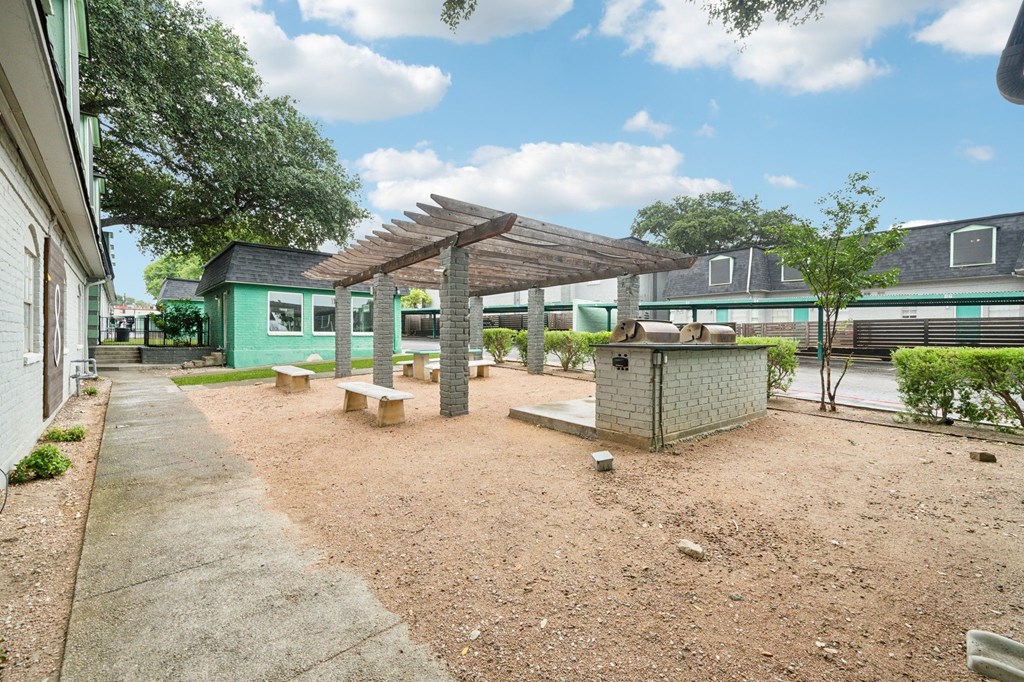 a picnic area with benches and a grill in front of a building