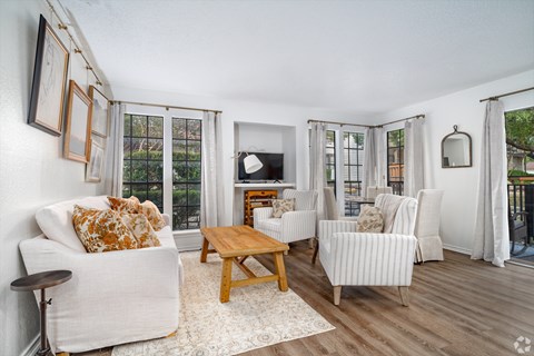 A living room with a white couch, a wooden coffee table, and a television.