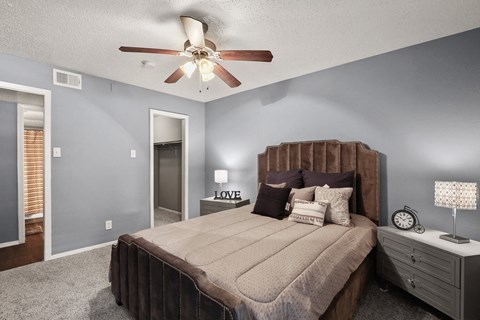 the master bedroom has a king sized bed and a ceiling fan